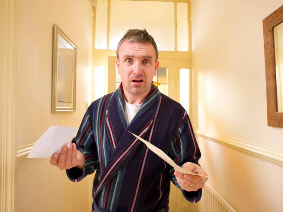 Nebenkostenabrechnung prüfen, Mann mit verständnislosem Gesicht steht im Hausflur und hält Nebenkostenabrechnung in der Hand, Foto: iStock/sturti